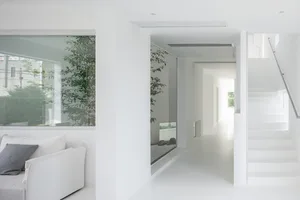 Contemporary white living room with minimalist design, white furniture, and large windows