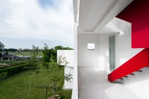 A minimalist exterior with white walls and red metal accents