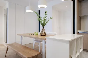 A minimalist kitchen with white oak cabinetry, white countertops, and white pendant lights.