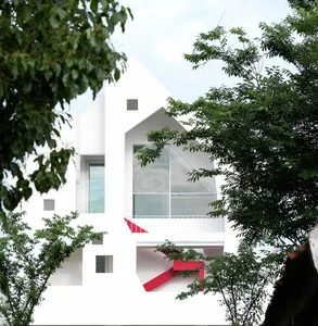A minimalist white exterior residential house surrounded by green trees.