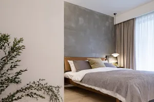 A stylish minimalist bedroom featuring a concrete accent wall and a wooden bedframe.