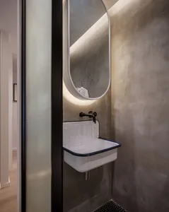 Industrial-style bathroom with concrete walls and a minimalist white sink.
