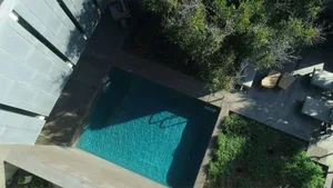 A modern, minimalist poolside area with a concrete surface and a clean, rectangular pool.