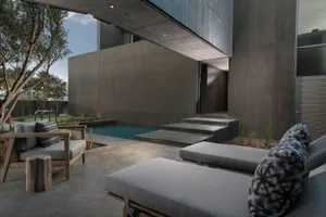 A modern residential exterior featuring concrete walls and a pool area.