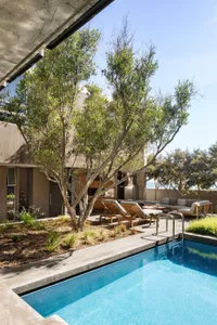 Modern residential exterior featuring concrete walls, glass doors, and wooden seating.