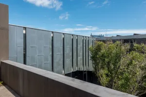 Minimalist building with metallic wall panels against a blue sky.