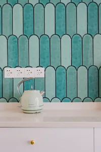 A modern kitchen with a white countertop and blue ceramic tiles on the wall.