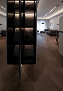Modern minimalist living room with dark wood floors, a grey sofa, and minimalist decor.