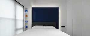 A minimalist bedroom featuring a white bed with blue accents.