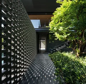 A modern minimalist garden featuring a black metal lattice wall and lush greenery.