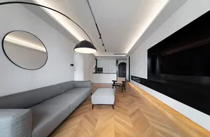 A modern minimalist living room featuring a wooden floor, metal accents, and glass elements.