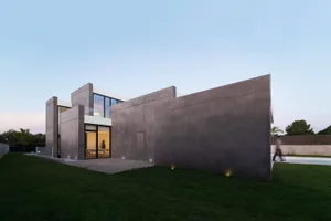 A modern residential home featuring a concrete exterior with large windows.