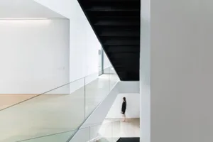 A modern interior design showcasing a glass staircase with black wooden steps.