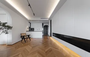 A modern kitchen with white cabinets, a black countertop bench, and a wooden floor.