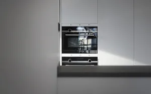 A sleek, modern kitchen featuring a built-in oven with a glass door and stainless steel trim.