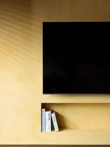 A modern, minimalist living room featuring a sleek TV mounted on a textured, concrete wall.