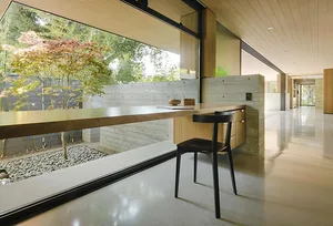 Modern minimalist office space featuring a concrete desk with a large window beside it.