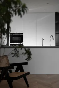 Modern minimalist kitchen with white cabinets, black kitchen island, and steel faucet.