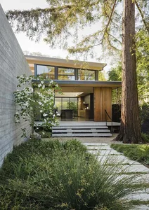 A modern residential house with a combination of concrete, wood, and glass materials.