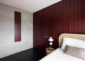 Modern bedroom featuring burgundy accent wall and rattan bedding