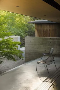 A modern outdoor space featuring concrete paving, a wooden wall, and greenery.