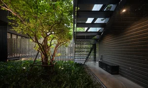 Modern interior courtyard featuring a staircase with metal and concrete elements surrounded by greenery.