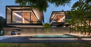 A modern house exterior featuring a concrete structure with large windows and a pool at night