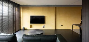 Modern living room with a black leather sofa, wooden coffee table, and a large window with blinds.
