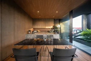 A modern residential kitchen featuring a marble countertop with stainless steel appliances and black chairs.