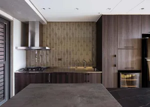 A modern kitchen with metallic surfaces, wooden cabinets, and glass backsplash.