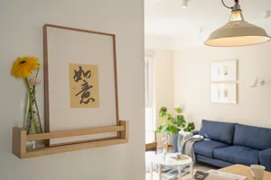 A modern living room featuring a blue sofa, white walls, and a plant on a white table.
