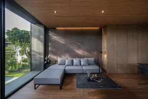 Modern living room featuring a grey sectional sofa with cushions, a black marble coffee table, and a large window overlooking