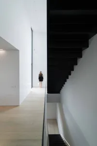 A minimalist white interior space with a sleek, black, modern staircase.