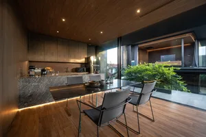 Modern residential dining room featuring a marble table, stainless-steel appliances, and wood finishes.