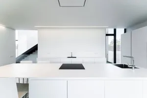 Modern minimalist kitchen with white laminates and a black countertop.