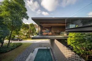 A modern house featuring glass, concrete, and stone materials with a minimalist design.