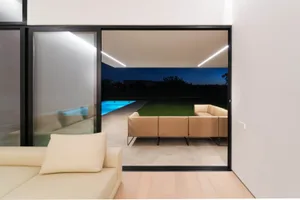 Modern backyard with glass door and outdoor seating area.