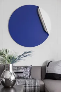 A sleek, modern blue and white circular artwork hanging on a textured white wall.