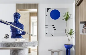 A contemporary entryway with polished concrete floors, a blue marble sculpture, and a blue and white geometric painting.