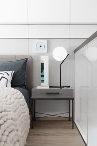 Minimalist bedroom featuring a bedside table, lamp, and decorative items.