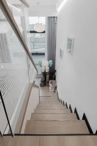 Modern minimalist staircase with wooden steps and metal railings, leading down to a lower level of a residential home.