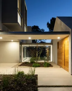 Modern entryway featuring a concrete and glass planter with wooden door and lighting.