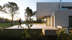 Modern house featuring concrete and glass exterior with a poolside setting.