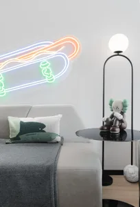 A modern living room featuring a contemporary table lamp with a round shade, a gray sofa with a green and white throw pillow,