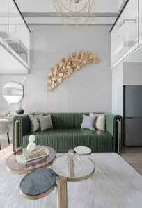 Modern interior design featuring a green sofa, round coffee tables, and decorative wall art.