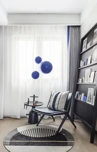 Minimalist living room featuring a black wooden chair, floating blue ball decorations, and a striped rug.