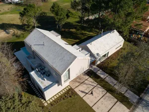 A modern, concrete residential home with a pool and garden