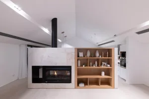 Modern lounge area with white materials and a fireplace.