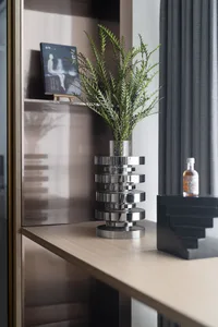 A minimalist living space adorned with a metallic botanical display on a wooden shelf.
