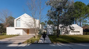 一棟擁有白色混凝土外牆的現代住宅建築，坐落於清澈藍天之下。